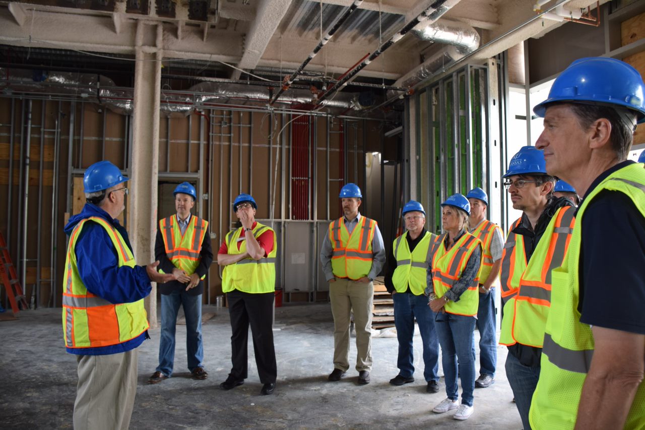 People wearing construction vests and hard hats tour the Integrated Science Building while it's under construction